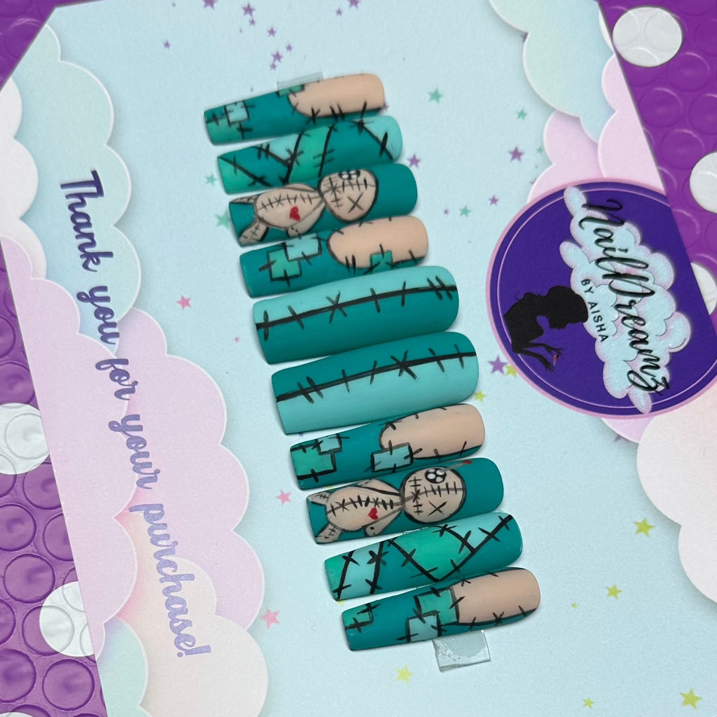 Full set of voodoo doll press on nails with stitched teal and nude patchwork, doll heart accent nail displayed diagonally on Nail Dreamz card.
