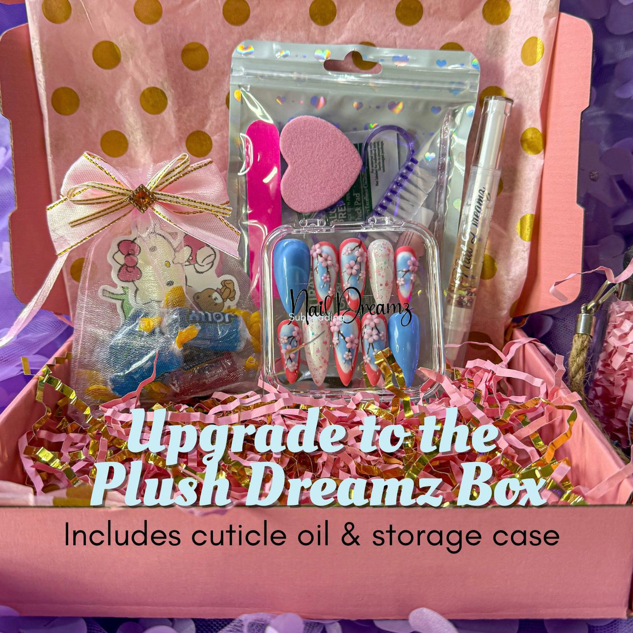 Plush Dreamz Box filled with press on nails, pink heart buffer, nail prep tools, cuticle oil pen, and a mesh gift bag with fun extras on pink shredded filler