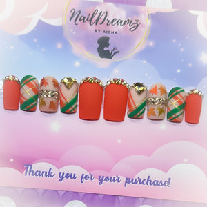 Close-up of orange plaid press on nails with gold rhinestone accents