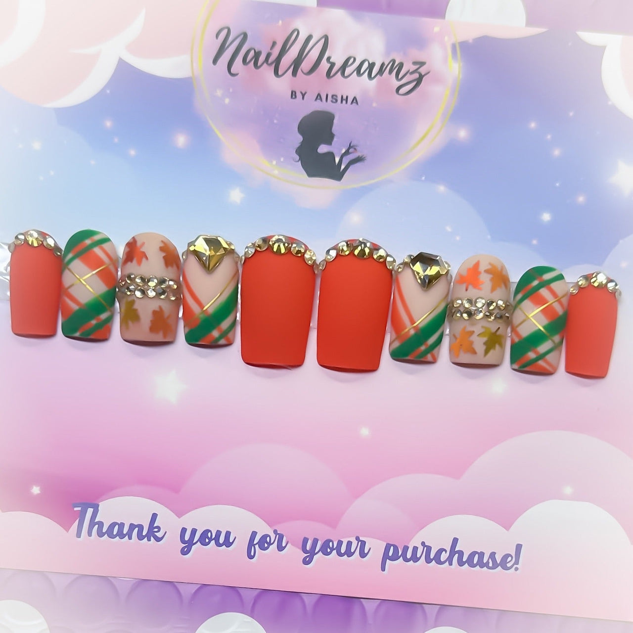 Close-up of orange plaid press on nails with gold rhinestone accents