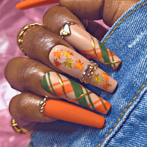 Hand model wearing autumn glow plaid nails with rhinestones and leaves