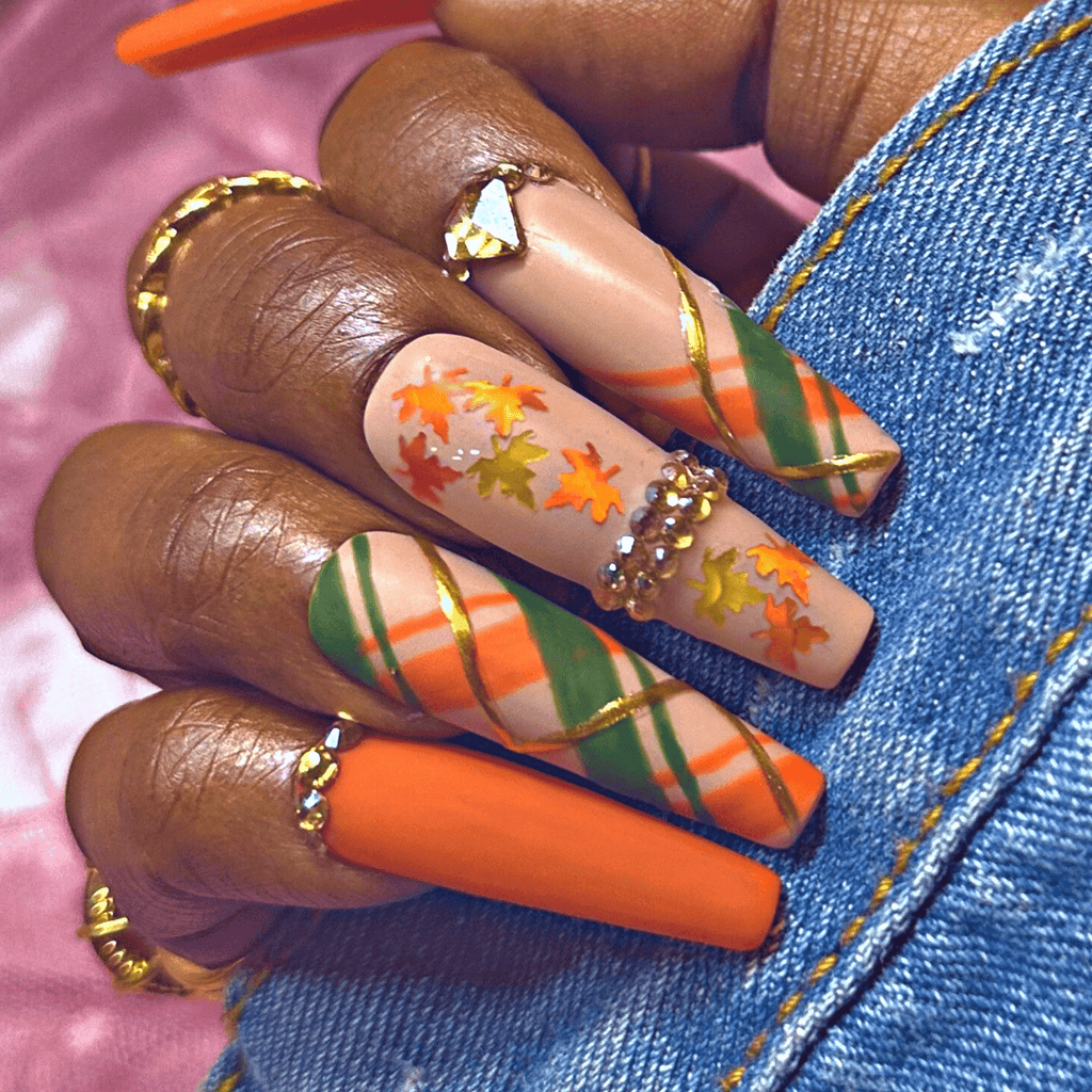 Hand model wearing autumn glow plaid nails with rhinestones and leaves