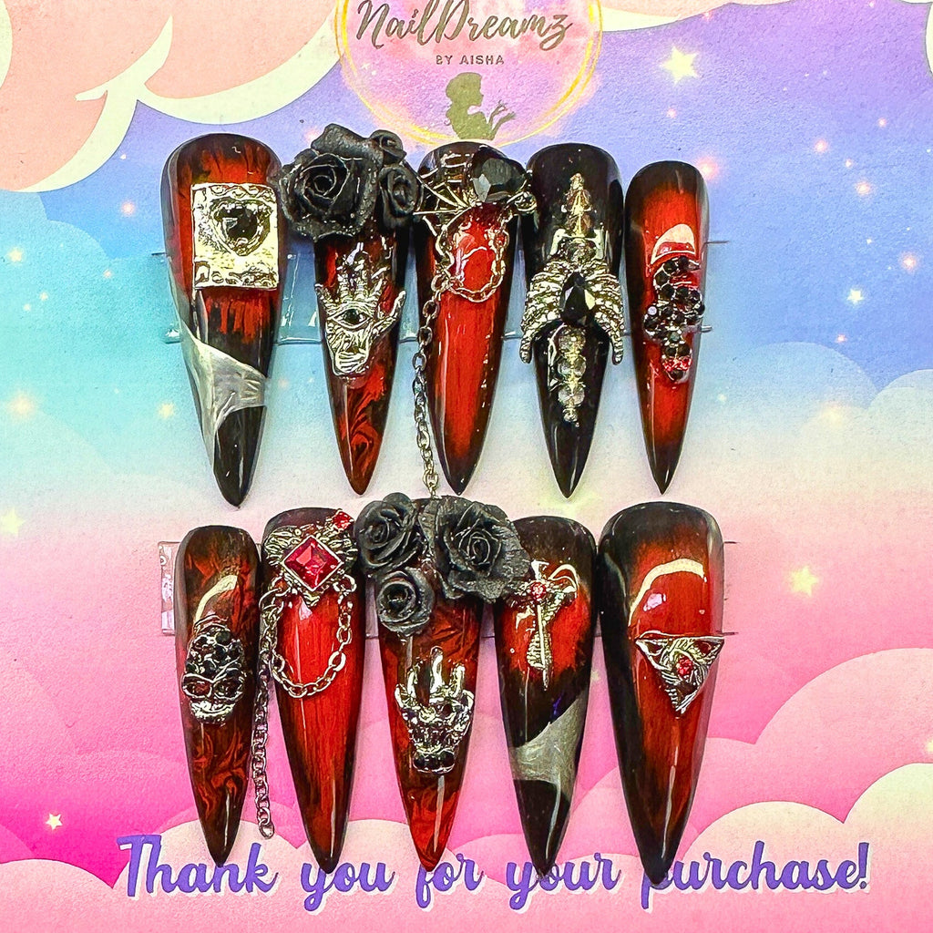 Gothic red and black Halloween press on nails with chrome, roses, chains, and skull charms on marbled base