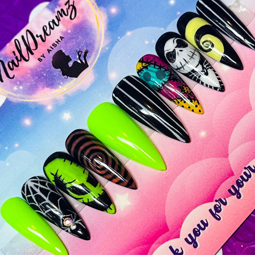 close-up of nightmare before christmas press-on nails—neon green & black with oogie boogie, jack, spiderwebs; long stiletto tips